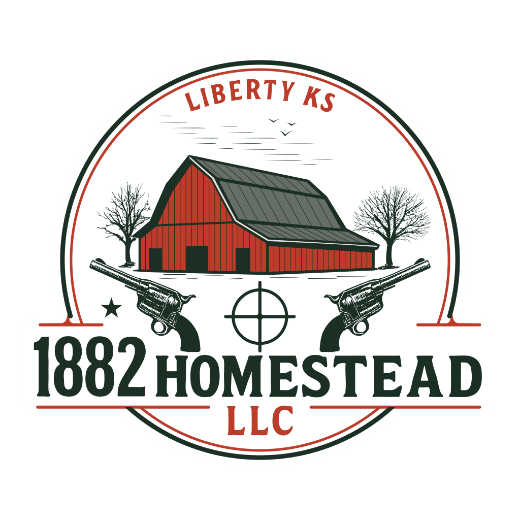 Logo of 1882 Homestead LLC featuring a red barn with a gray roof, two leafless trees, and flying birds, flanked by two vintage revolvers. Below the barn, a target crosshair symbol is centered between the revolvers. 'LIBERTY KS' is written above the barn, and '1882 Homestead LLC' is prominently displayed below.